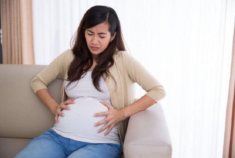 Hình ảnh minh họa cảm giác buồn nôn và ốm nghén khi mang thai tuần đầu với hình ảnh một người phụ nữ đang ôm bụng, mặt hơi xanh xao và cảm thấy khó chịu.